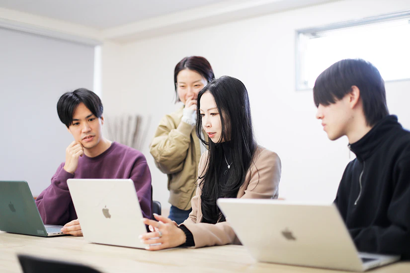 ノートPCを前に4人のメンバーがディスカッションしている様子。
