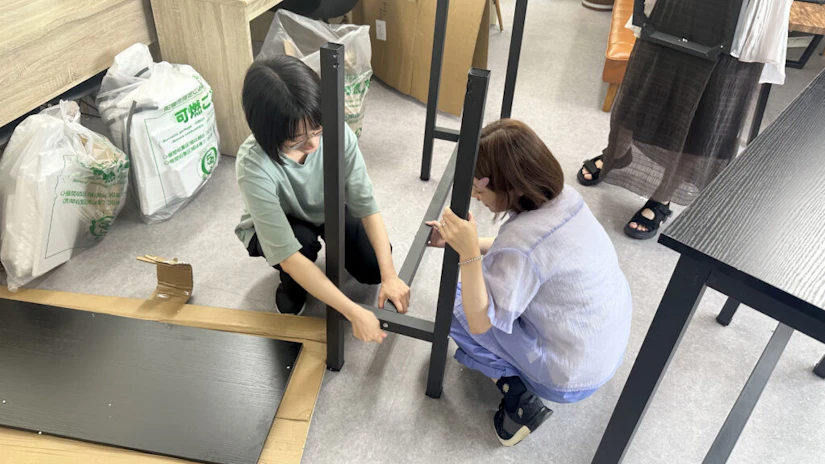 デスクを協力して組み立てるノベルティメンバー