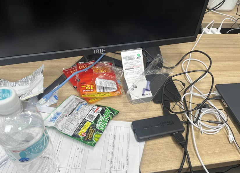 パソコンデスク。ホッカイロや、空のペットボトル、ゴミがいくつか散乱している。