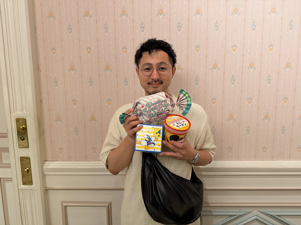 お土産を抱えて笑顔の男性社員の写真。