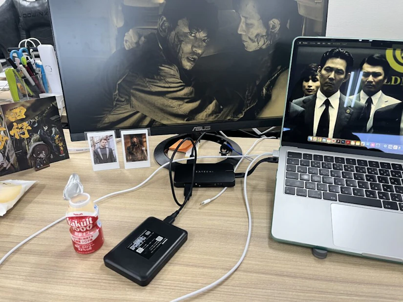 パソコンデスク。デスクトップには映画のワンシーン。アクリルスタンドや、写真が何枚も立てかけられている。