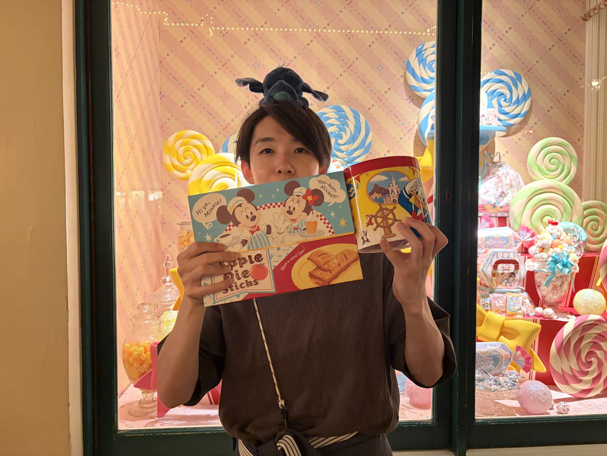 お土産を顔の前で掲げる男性社員の写真。