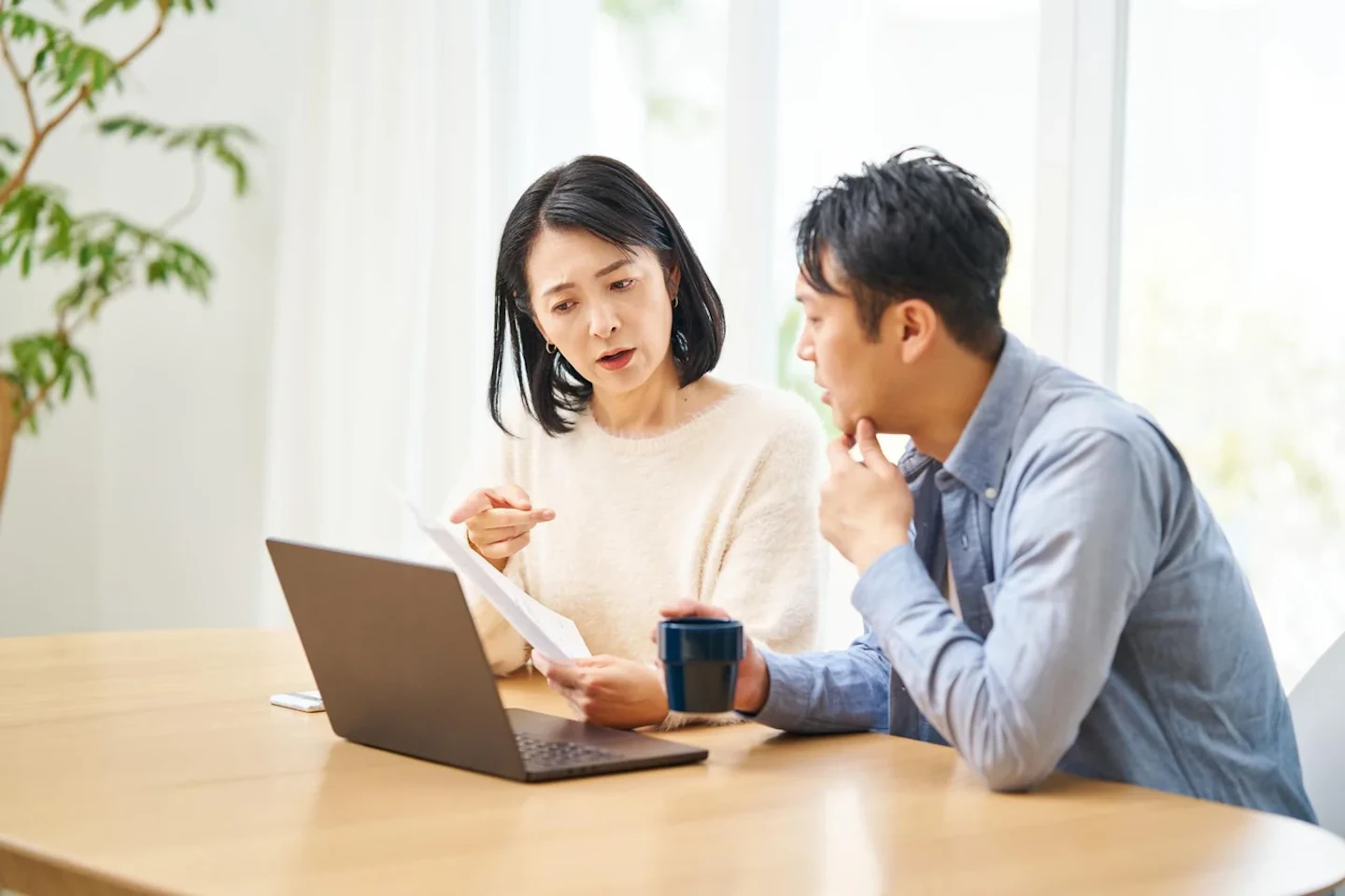 検針票を見ながら電気料金を確認する夫婦（電力会社の乗り換え検討）