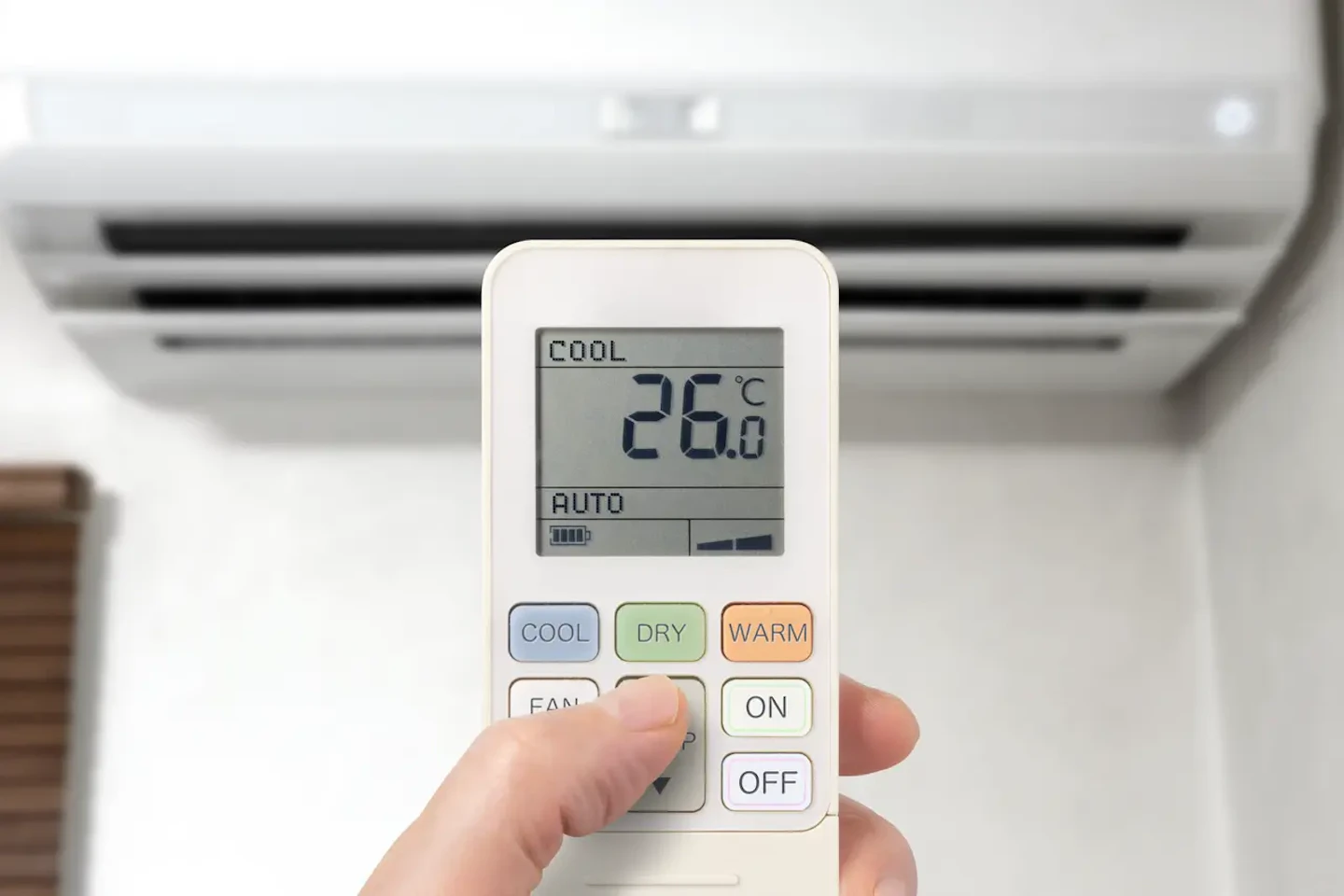 エアコンのリモコンを操作する手（冷房設定・節電）