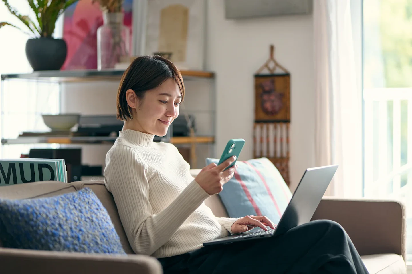 スマートフォンとパソコンで電気料金を比較する女性（乗り換え前の試算）