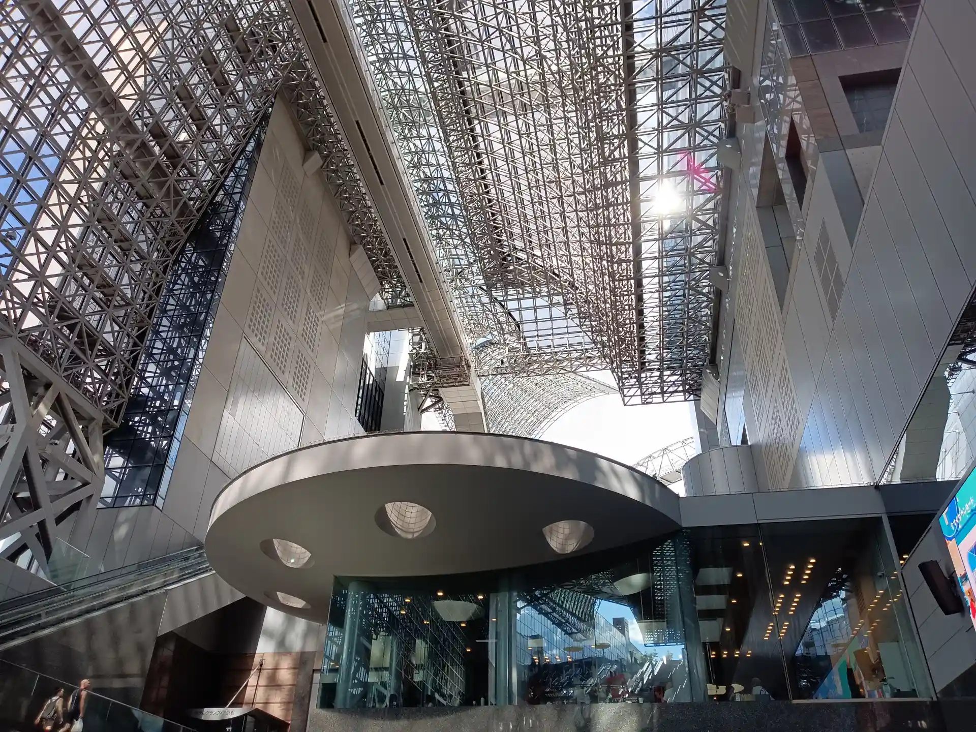 Kyoto Station atrium area on the route from the Central Side to the Hachijo Side, with glass and steel architecture overhead