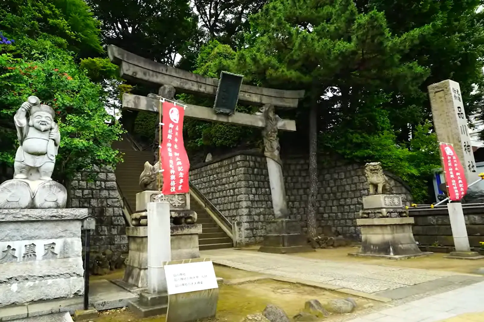 Entrance to Shinagawa Shrine featuring torii gate and guardian statues, including Daikokuten