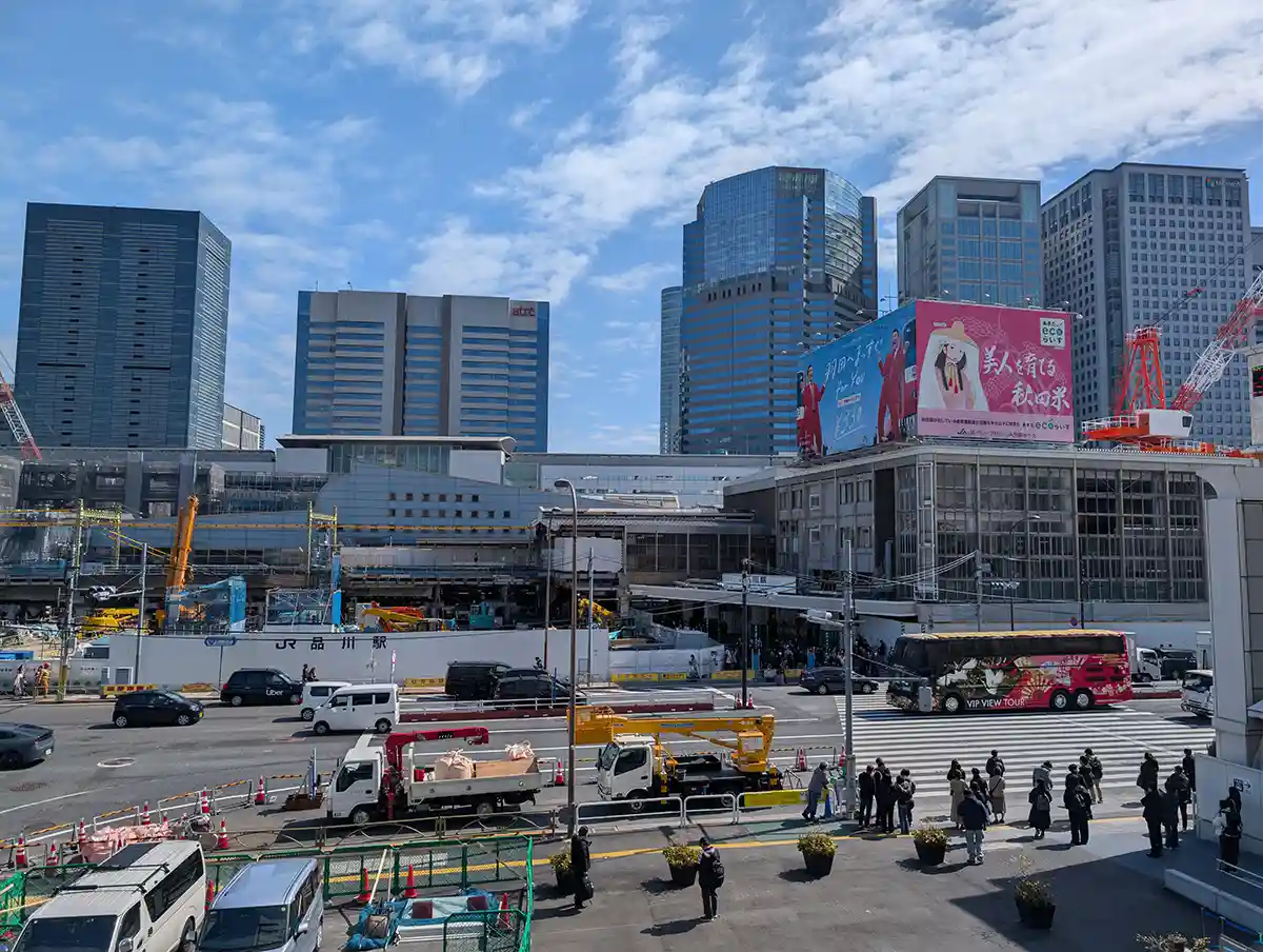 Takanawa West side area of Shinagawa Station with station building, road crossing, and nearby towers
