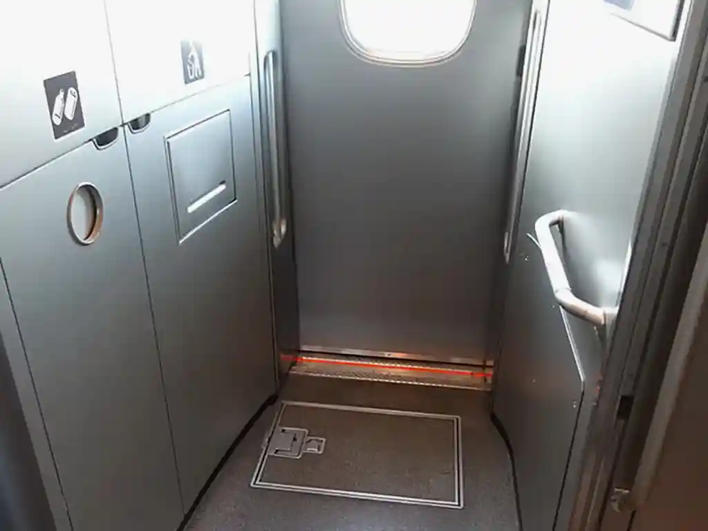 Onboard trash disposal bins with icons for bottles, cans, and general waste on a Shinkansen