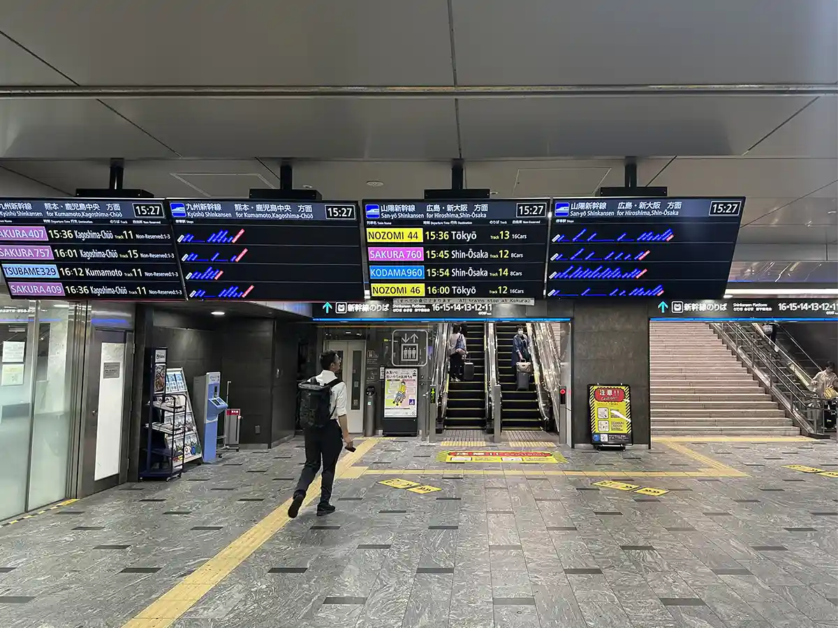 Shinkansen departure boards inside Hakata Station showing train times, platforms, and destinations