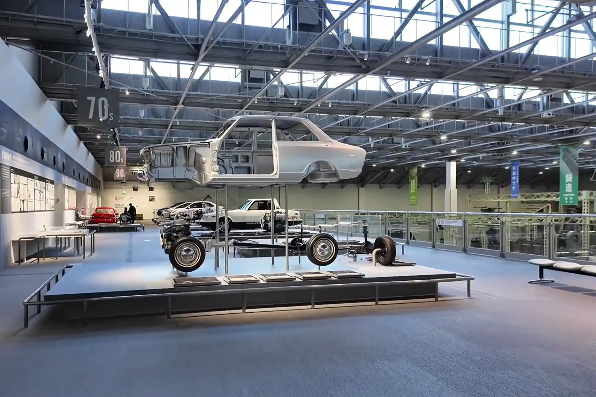 Exhibition area at the Toyota Commemorative Museum of Industry and Technology showing an assembled chassis and suspended vehicle body