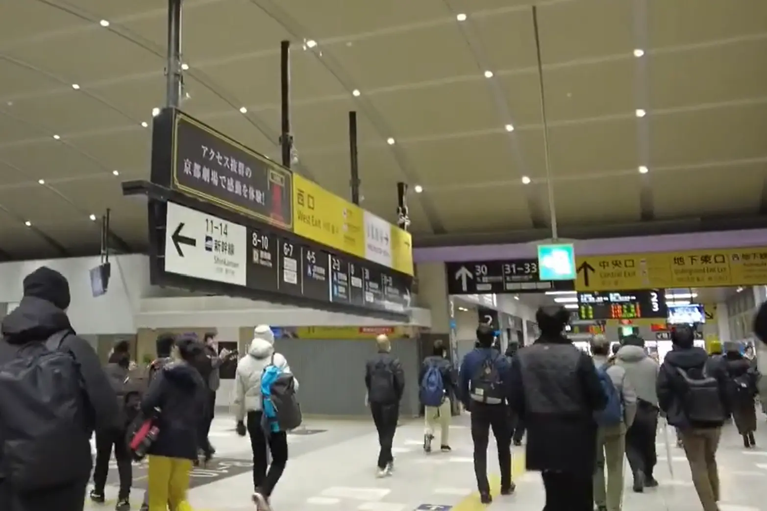 Kyoto Station 2F concourse with direction signs guiding passengers toward the Shinkansen gates and JR platforms