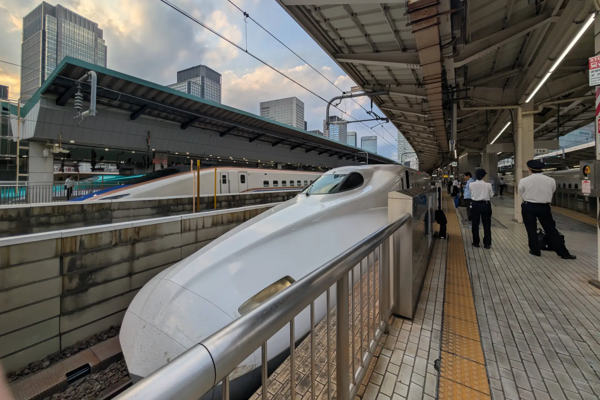 Shinkansen trains at Tokyo Station with passengers and railway staff on the platform