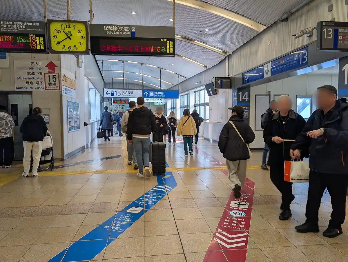JR concourse at Shinagawa Station above Narita Express platform with passengers and signs to the Shinkansen platforms