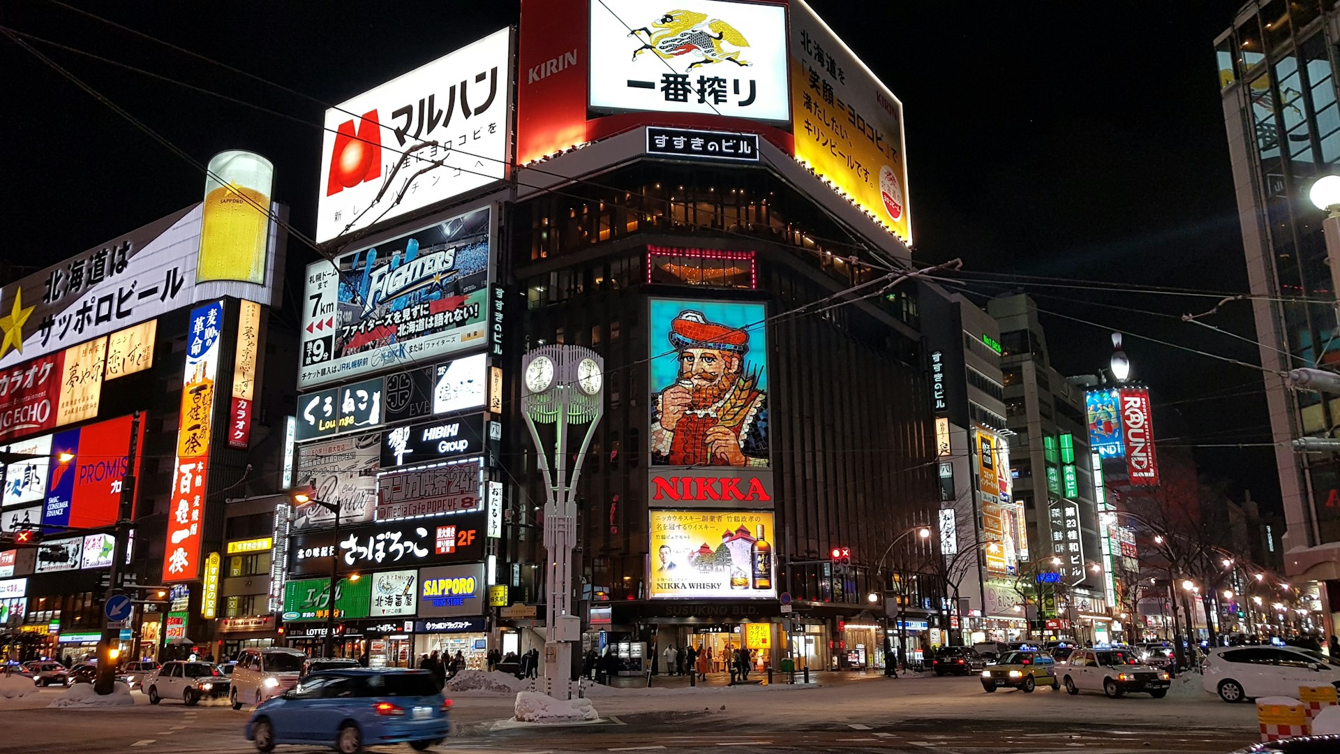 Downtown Sapporo at night with illuminated signs and busy streets, representing the city center travelers visit after reaching Hokkaido