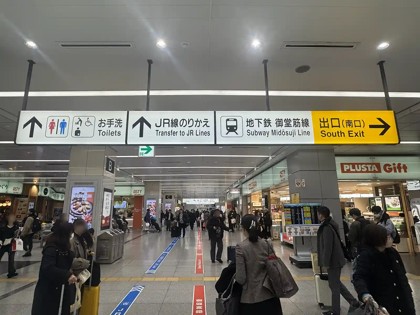 Shin-Osaka Station transfer area with clear signs guiding passengers from the Shinkansen to JR Lines and subway exits