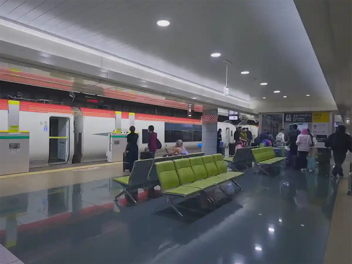 JR Narita Airport station platform with Narita Express train and seating area for travelers