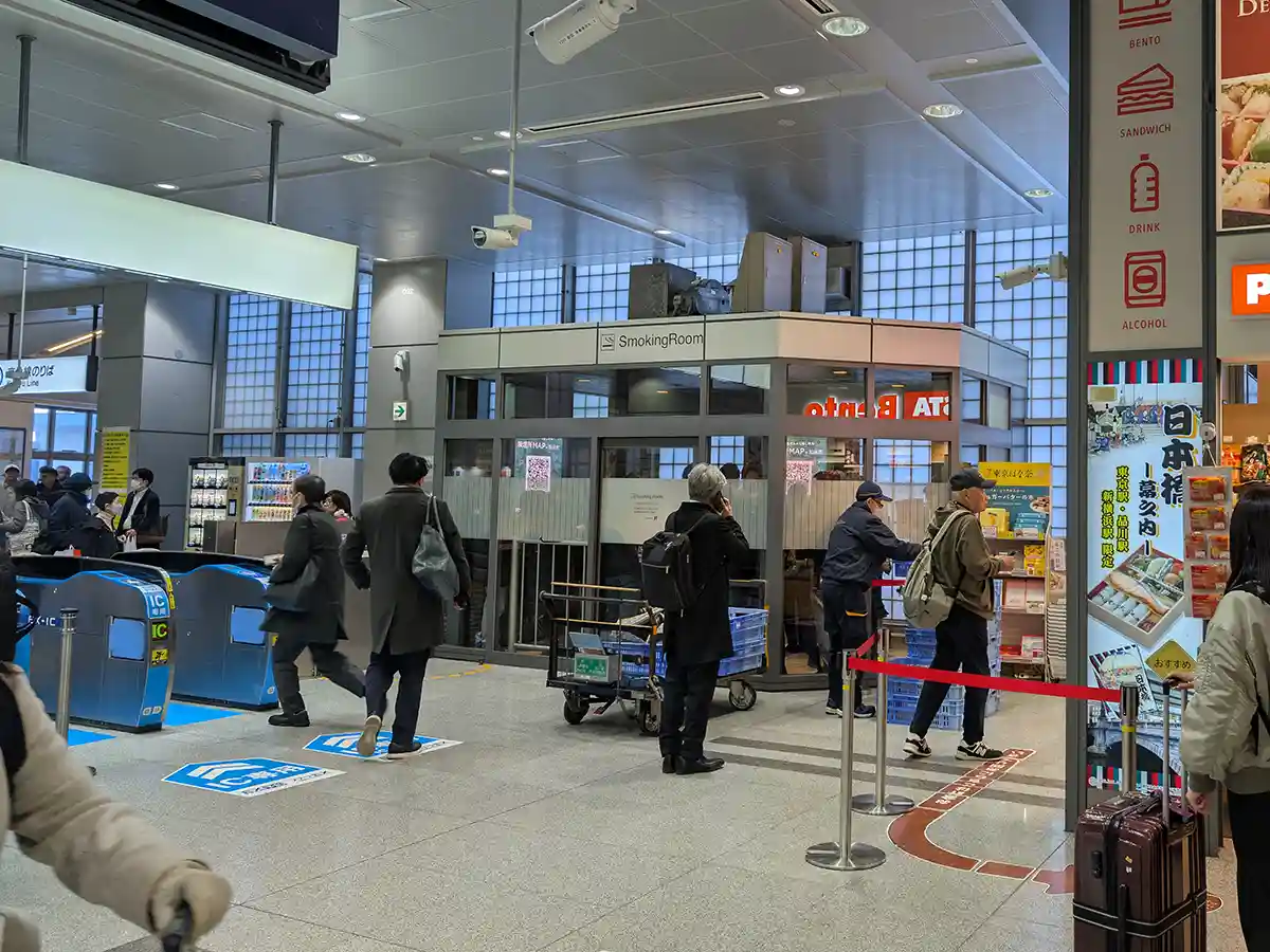 Small smoking room in Shinagawa Station Shinkansen area near the south transfer gate with passengers nearby