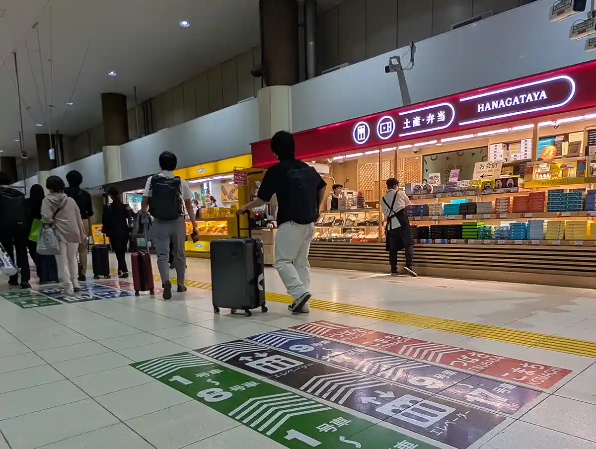 Ekiben shop inside JR Ueno Station Shinkansen gate area with travelers and luggage nearby
