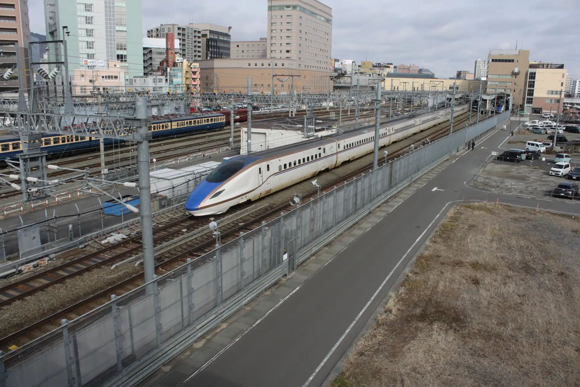 Kagayaki Shinkansen train running between Tokyo and Nagano with city buildings in the background