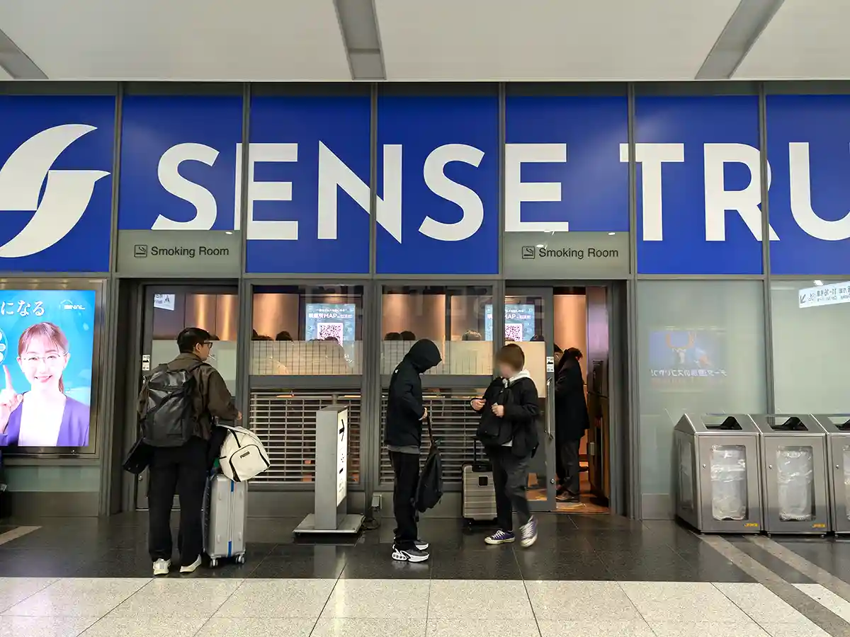 Smoking room inside Shinagawa Station Shinkansen concourse with passengers entering the designated area
