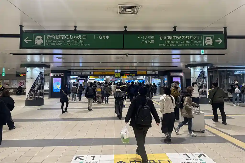 Concourse inside Sendai Station after passing the local train gates, with travelers moving toward transfer routes.