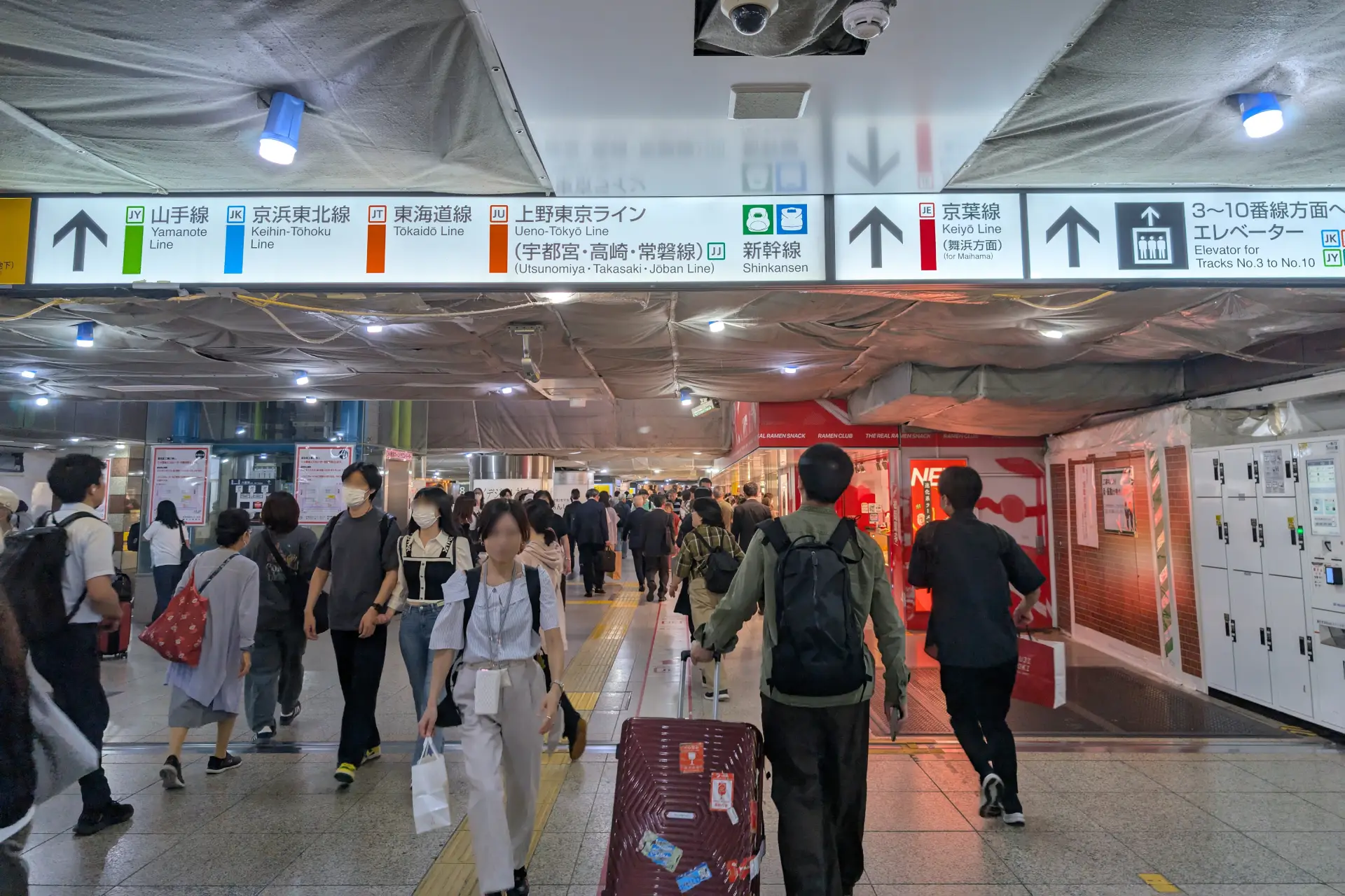 Tokyo Station concourse showing JR line transfer signage and commuters