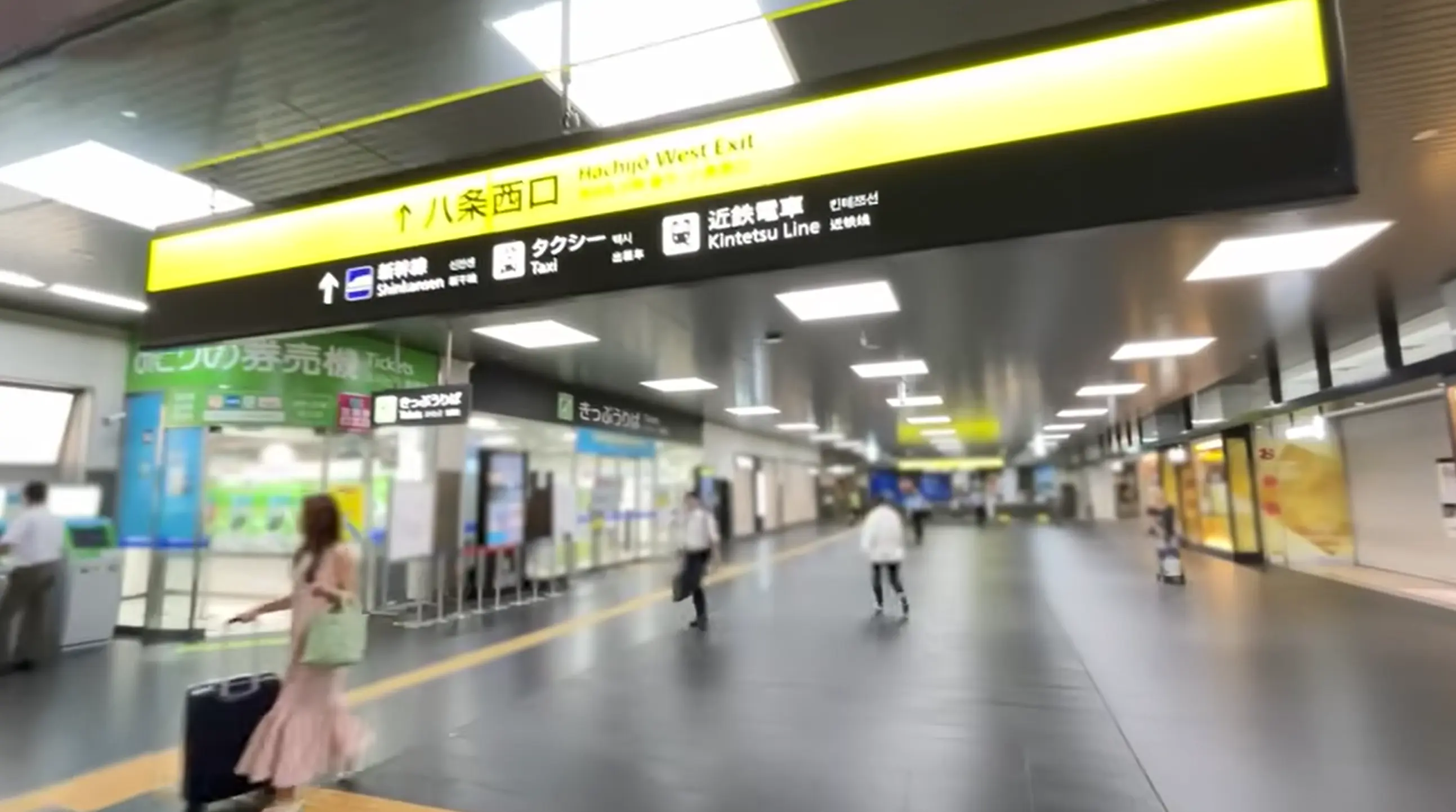 North–South Pedestrian Deck inside Kyoto Station with a large sign directing travelers to the Hachijo West Exit and Shinkansen