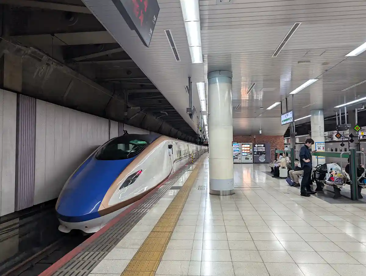 Shinkansen train stopped at Ueno Station platform with passengers waiting nearby