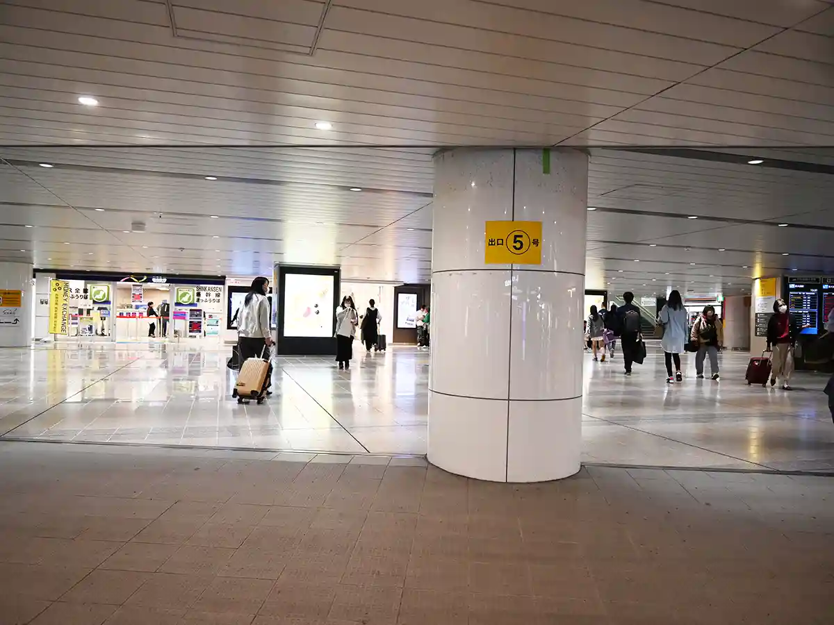 Exit 5 sign in Shin-Osaka Station concourse after Midosuji Line ticket gates with passengers walking nearby