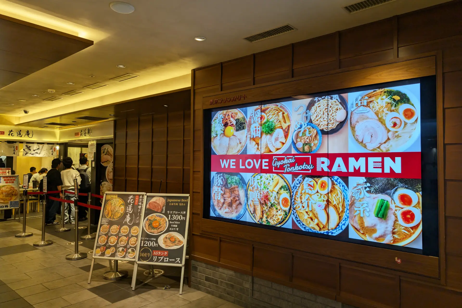 Tokyo Station Ichibangai ramen street with illuminated menu board and customers lining up