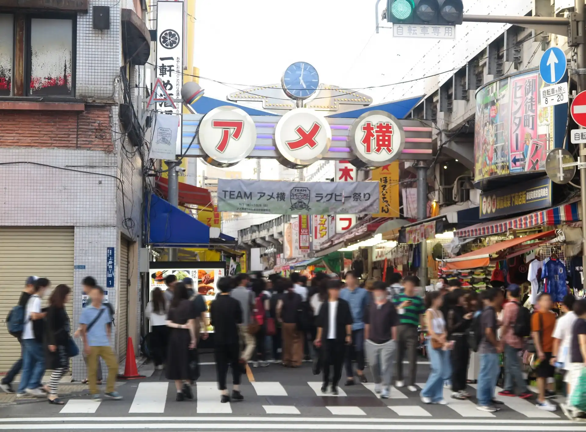 Crowded entrance of Ameyoko shopping street near Ueno Station with street sign and market stalls