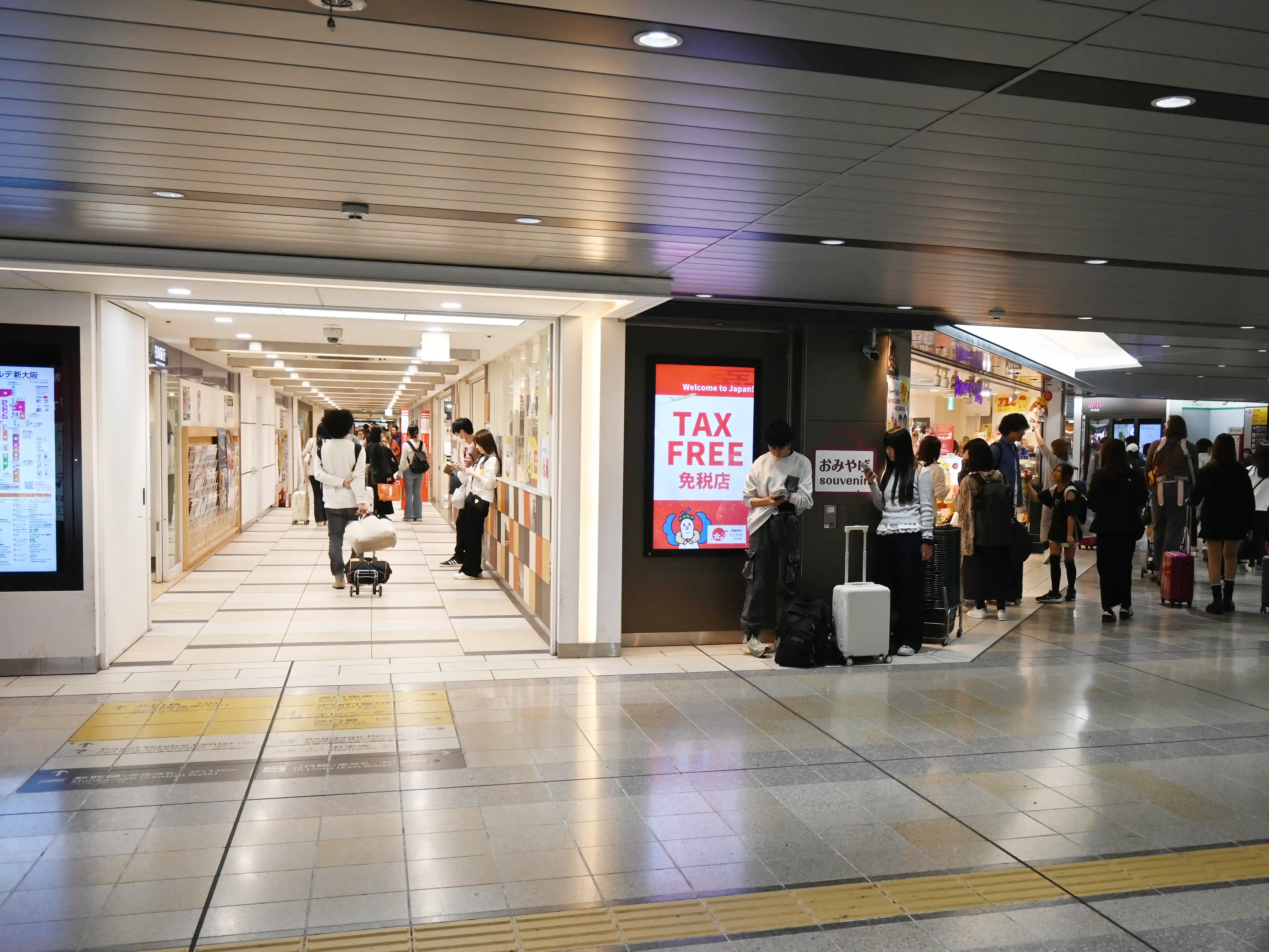 Shopping corridor near Exit 5 at Shin-Osaka Station with Nippon Travel and people walking through