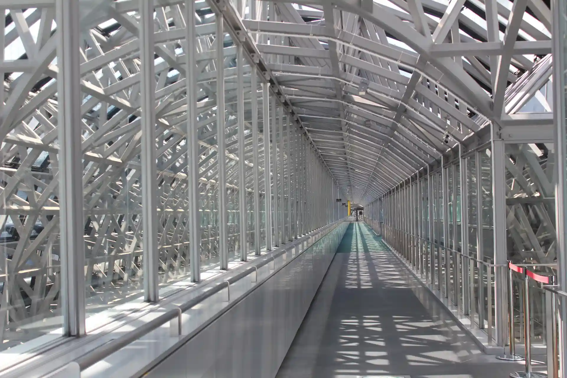 Glass-covered Skyway walkway inside Kyoto Station, showing the long elevated path with steel frames and natural light