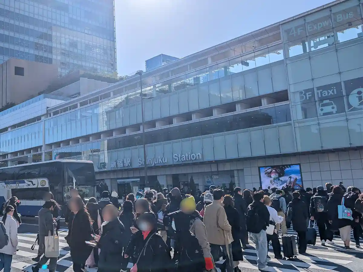 Busy crosswalk outside Shinjuku Station where many travelers and commuters walk across the street in Tokyo