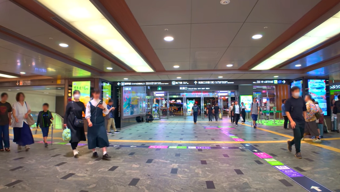 Hakata Station concourse with JR direction signs and floor navigation guides for passengers