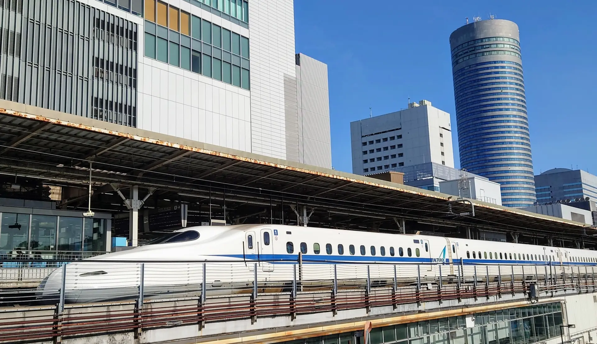 Shinkansen at platform in Shin-Yokohama Station, framed by modern skyscrapers
