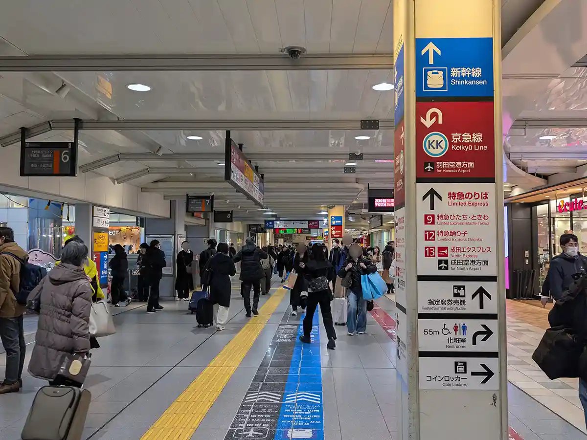 JR concourse at Shinagawa Station with passengers and signage pointing toward the Shinkansen platforms