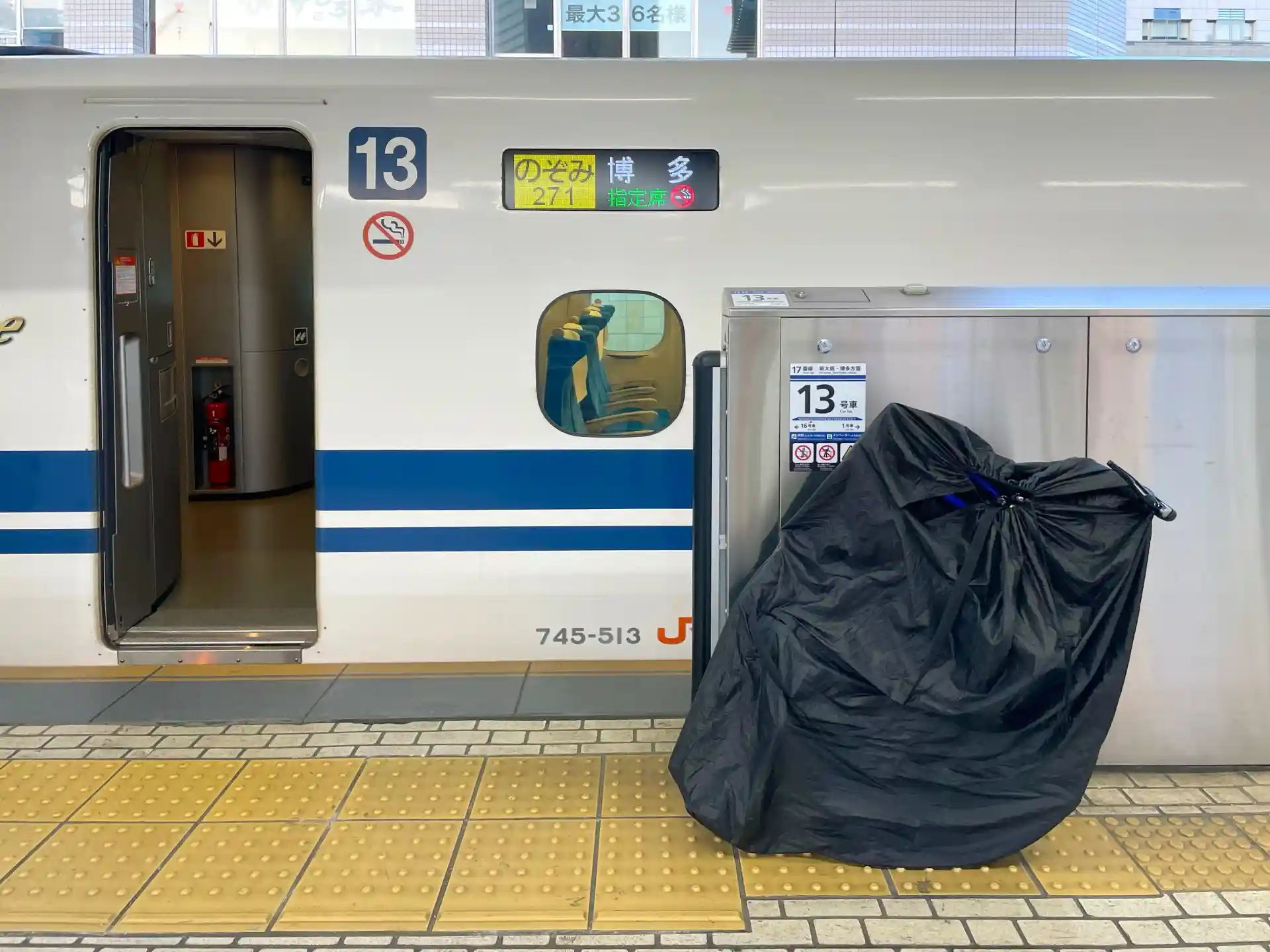 Large sports gear bag on a station platform next to a Shinkansen train before boarding.