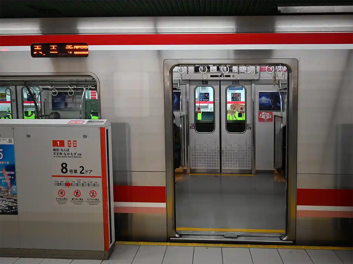 Osaka Metro Midosuji Line train stopped at Shin-Osaka Station with open doors and platform screen door
