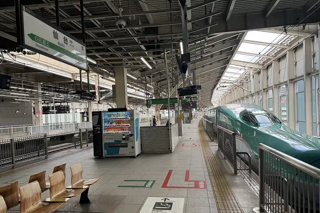 Shinkansen bound for Tokyo waiting at Sendai Station platform with platform signs and boarding area visible.