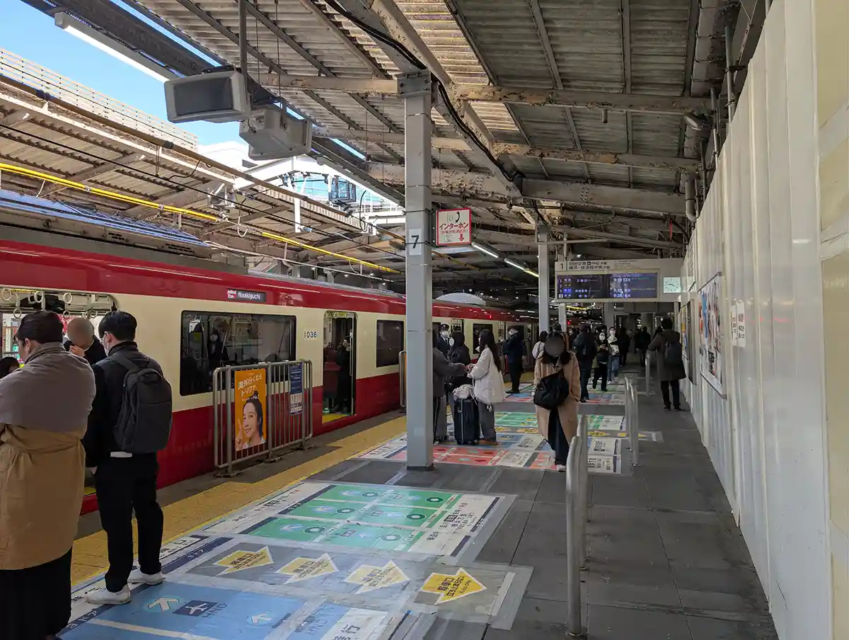 Passengers using Keikyu Line at Shinagawa Station platform with floor guides for boarding positions