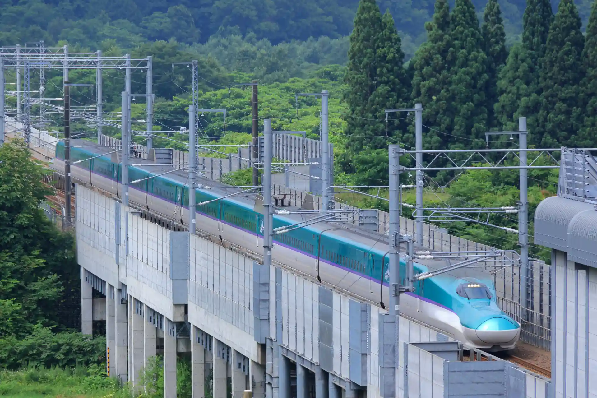 Hokkaido Shinkansen running through rural landscapes on an elevated track, part of the route connecting Tokyo with southern Hokkaido