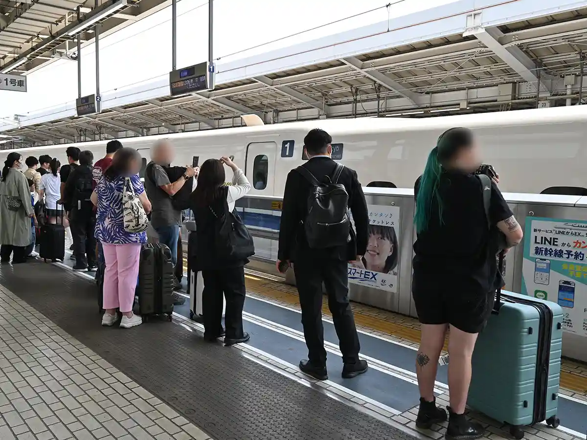 Travelers lining up at Shinkansen non-reserved boarding area with luggage on platform