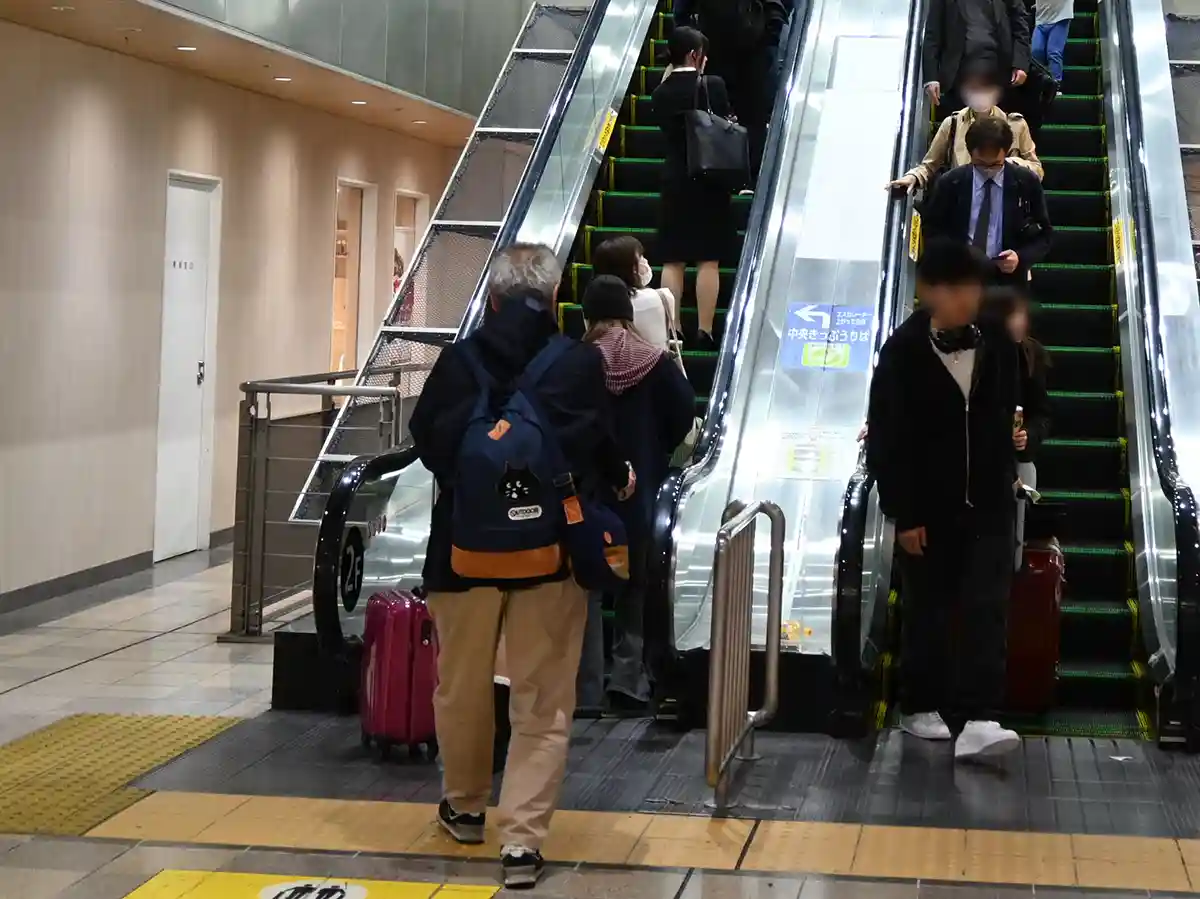 Escalators at Shin-Osaka Station leading from subway area toward Shinkansen concourse with passengers