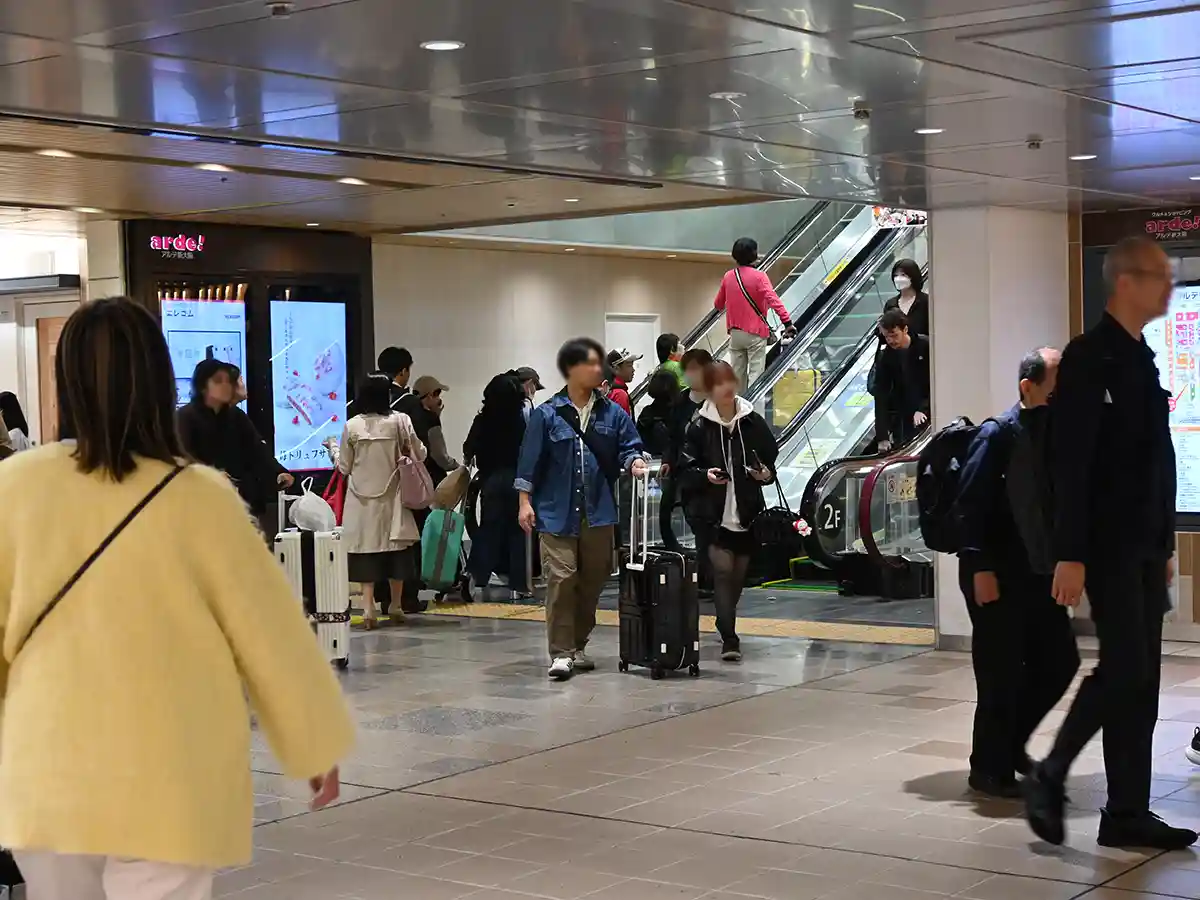 Escalator visible after corridor at Shin-Osaka Station with passengers walking toward upper level