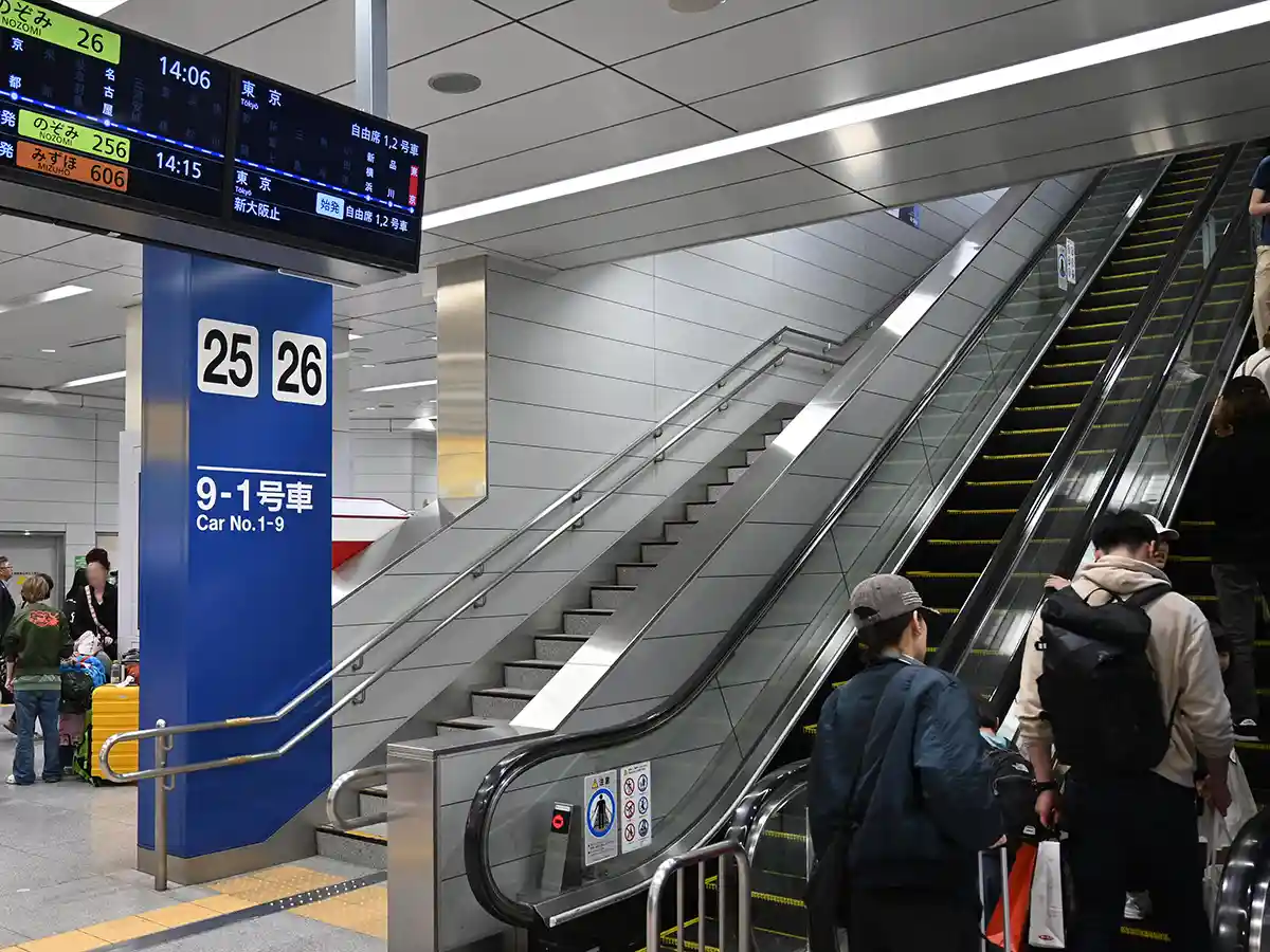 Escalator at Shin-Osaka Station leading up to Shinkansen platform with passengers going to tracks
