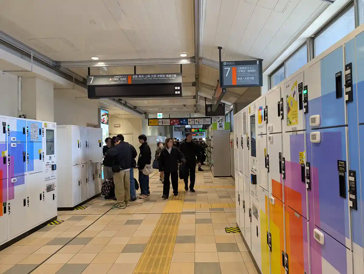 Coin lockers inside Shinagawa Station concourse with travelers storing luggage near the train platforms