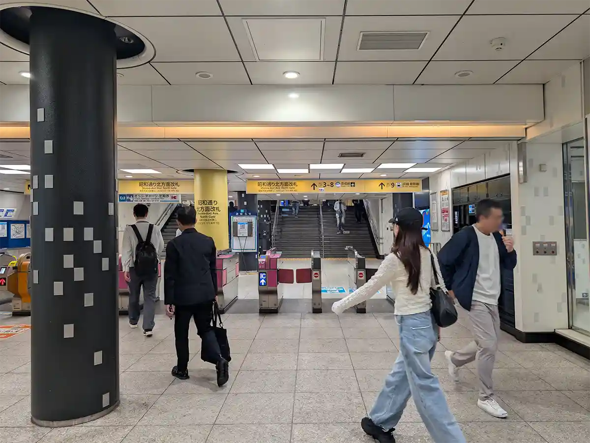 Tokyo Metro ticket gates at Ueno Station with passengers and signs for exits and JR transfer