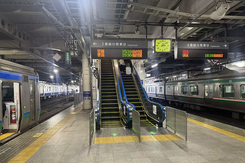 Escalator at the Sendai Airport Line platform guiding passengers up toward the Shinkansen transfer area at Sendai Station.